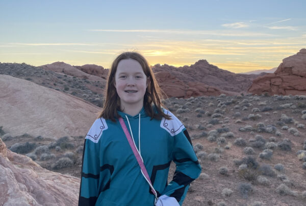 Cameron in the Valley of Fire State Park, at sunset with yellow and red clouds in the background. Standing on the side of a rocky hill.