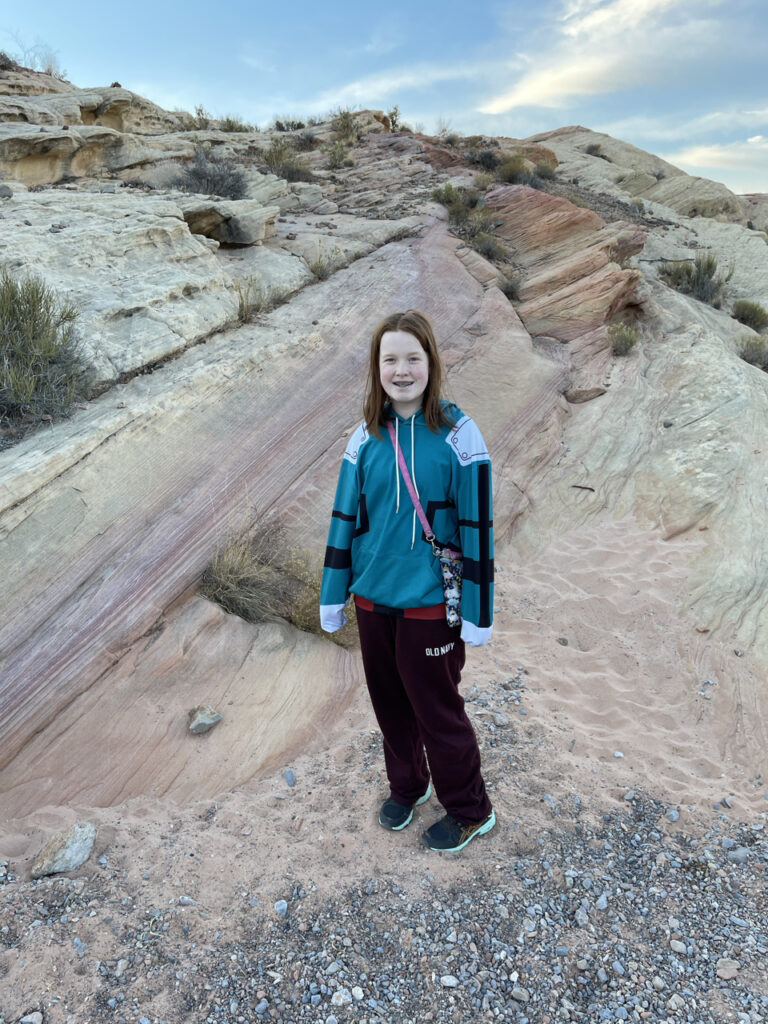 Cameron at the end of the hike for the Pastel Canyon Trail, with a wall of colorful rocks behind her. 