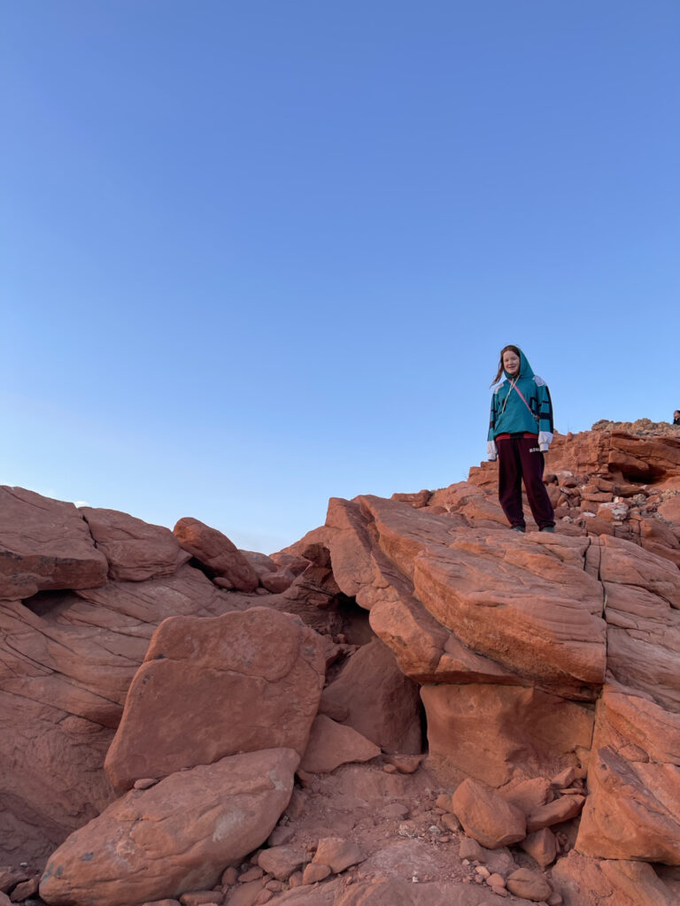 Cameron waiting for sunset, standing 25 feet above me on bright red rocks in the Valley of Fire State Park.