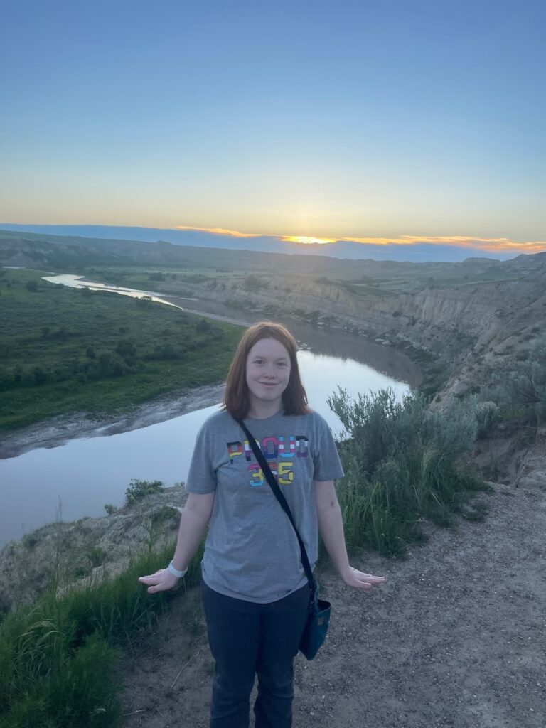 Cameron posing for a photo right at sunset on a high viewpoint overlooking a large bend in the Little Missouri River.