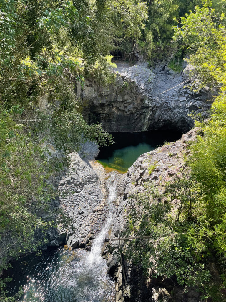 Looking down into a rocky pool of water and a waterfall in the jungle on the Pipiwai Trail in Haleakala National Park.