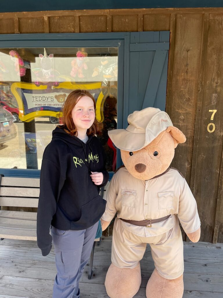 Cameron standing outside of a gift shop, next to a teddy bar that is almost as tall as she is. Right outside Theodore Roosevelt National Park.