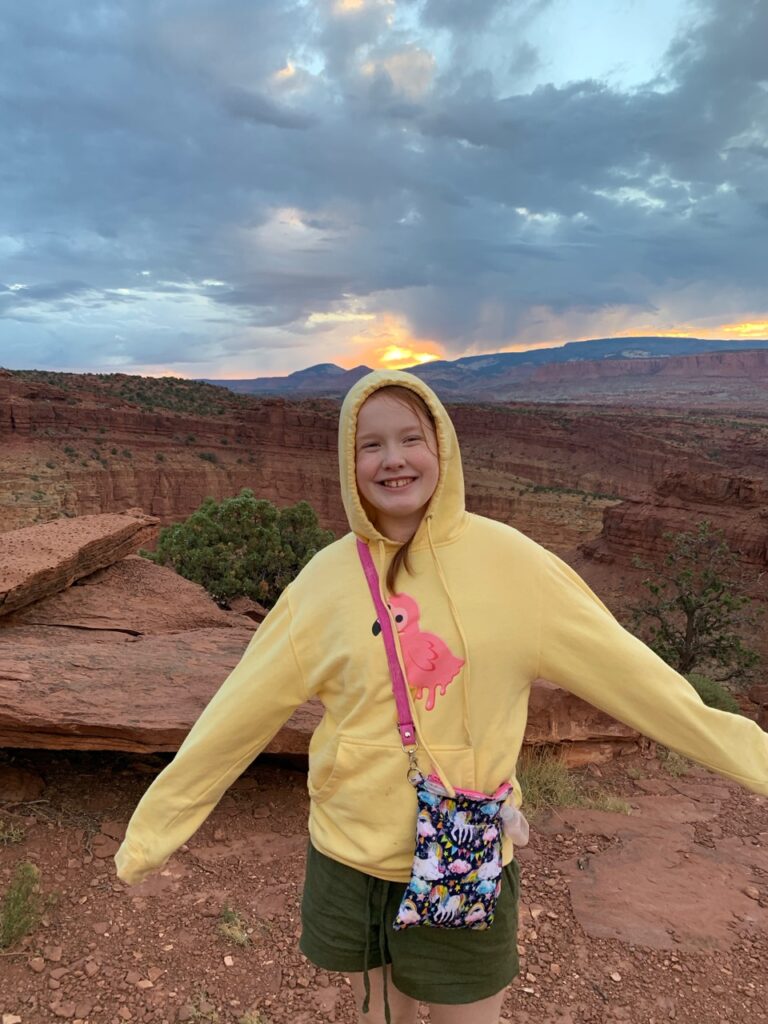 Cameron at sunset at Goosenecks Overlook in Capitol Reef with sky that has both color and storm clouds.