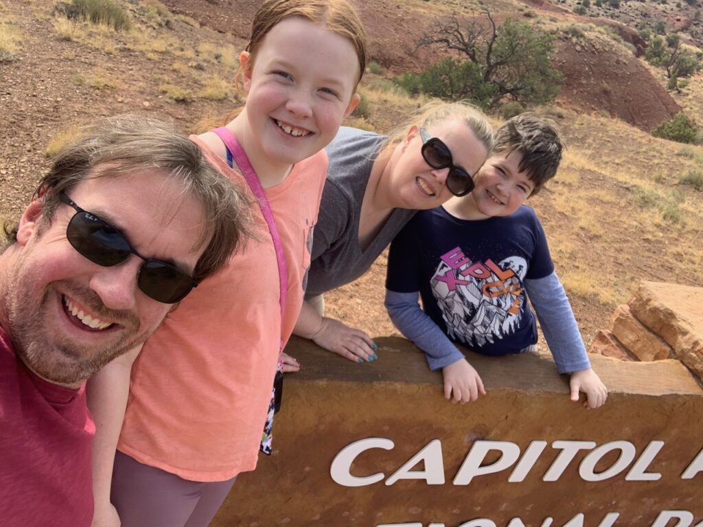 Cat, Cameron, Collin and myself standing on the park sign for Capitol Reef National Park.