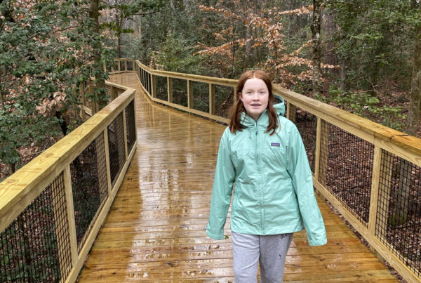 Cameron in her rain gear, starting her walk on the very wet boardwalk on the Firefly Trail in Congaree National Park.