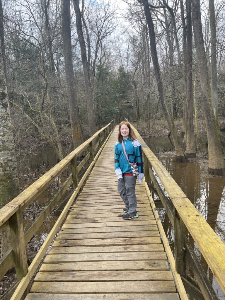 Cameron standing mid way on the main boardwalk on the Western Loop trail. Below and around us is a swamp full of old growth Cypress Trees. The photo was taken just after the rain had stopped but everything is still soaking wet.