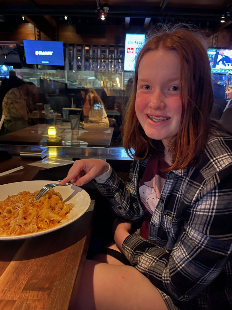 Cameron smiles as she sits at a restaurant in Waikiki eating a bowl of pasta. 