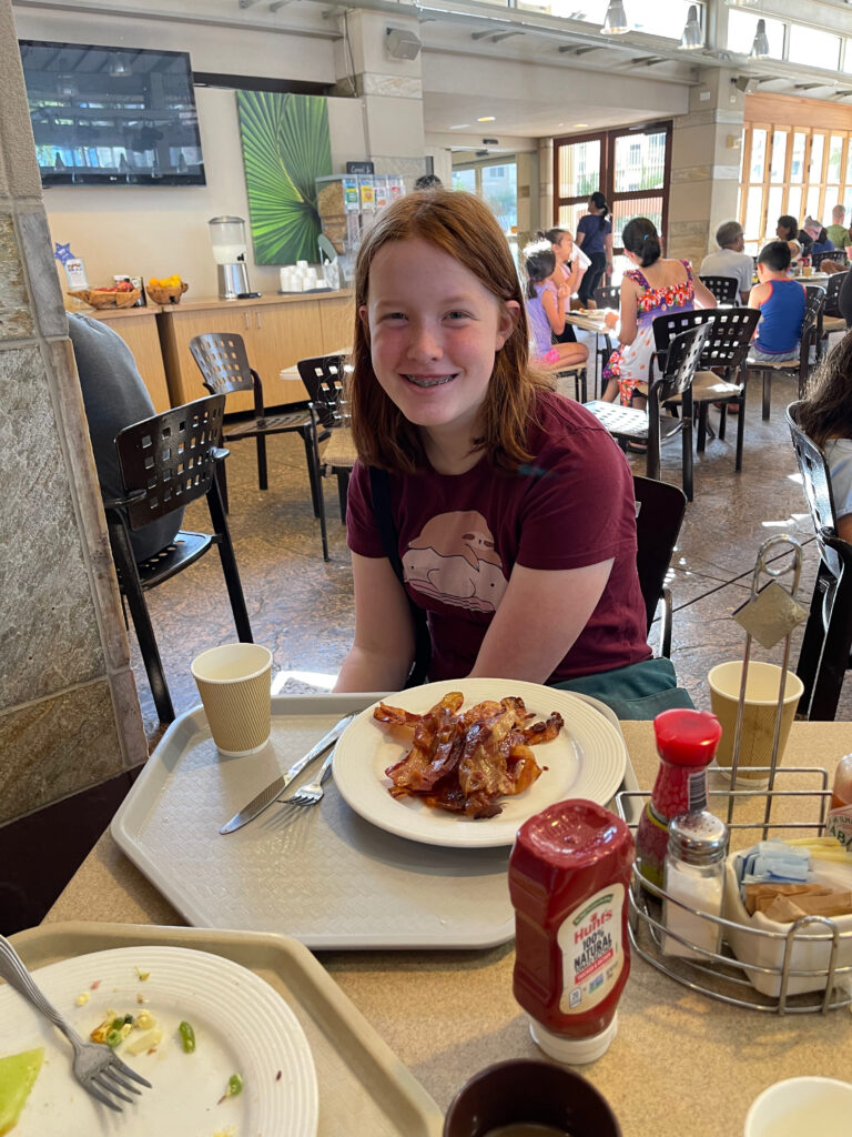 Cameron eating at the hotel for breakfast with a massive plate of bacon in front of her. 