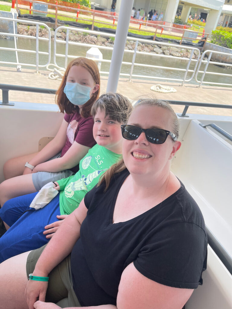 Cat, Collin and Cameron sitting on a bench seat on a the boat that takes you out to the USS Arizona in Pearl Harbor. 