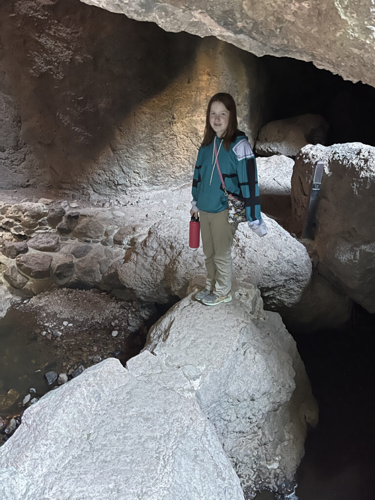 Cameron balancing on rocks inside the caves on the way to the top of the mountain in Pinnacles National Park. There are some cracks in the roof of the cave that allow sunlight to spill down into this room.