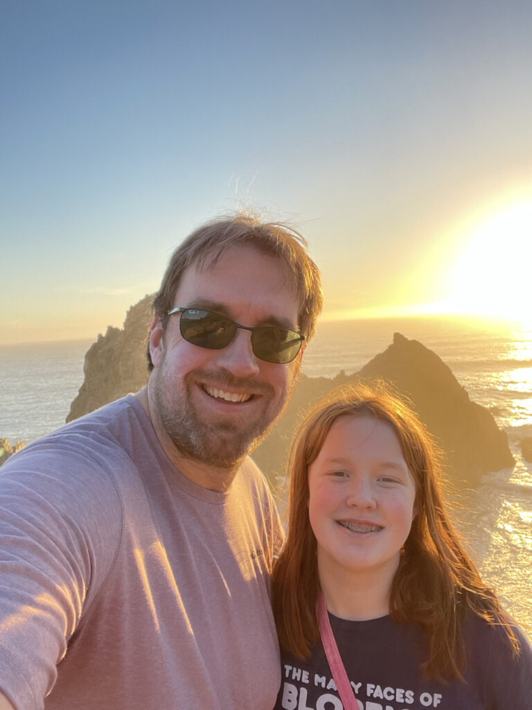 Cameron and myself back light by a stunning sunset, standing on top of the Dunes at Pfeiffer Beach in Big Sur with a massive sea stack behind us.