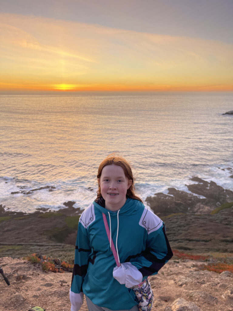 Cameron on the side of a cliff near Whale Peak in big Sur. Her hair both blowing in the wind and lit by the golden sunset light. Waves crashing below us on the rocky shoreline. 