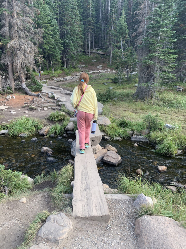 Cameron crossing a small creek on a fallen log on the Dream Lake trail in Rocky Mountain National Park.