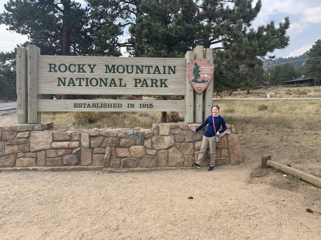 Cameron in front of the Rocky Mountain National Park sign.