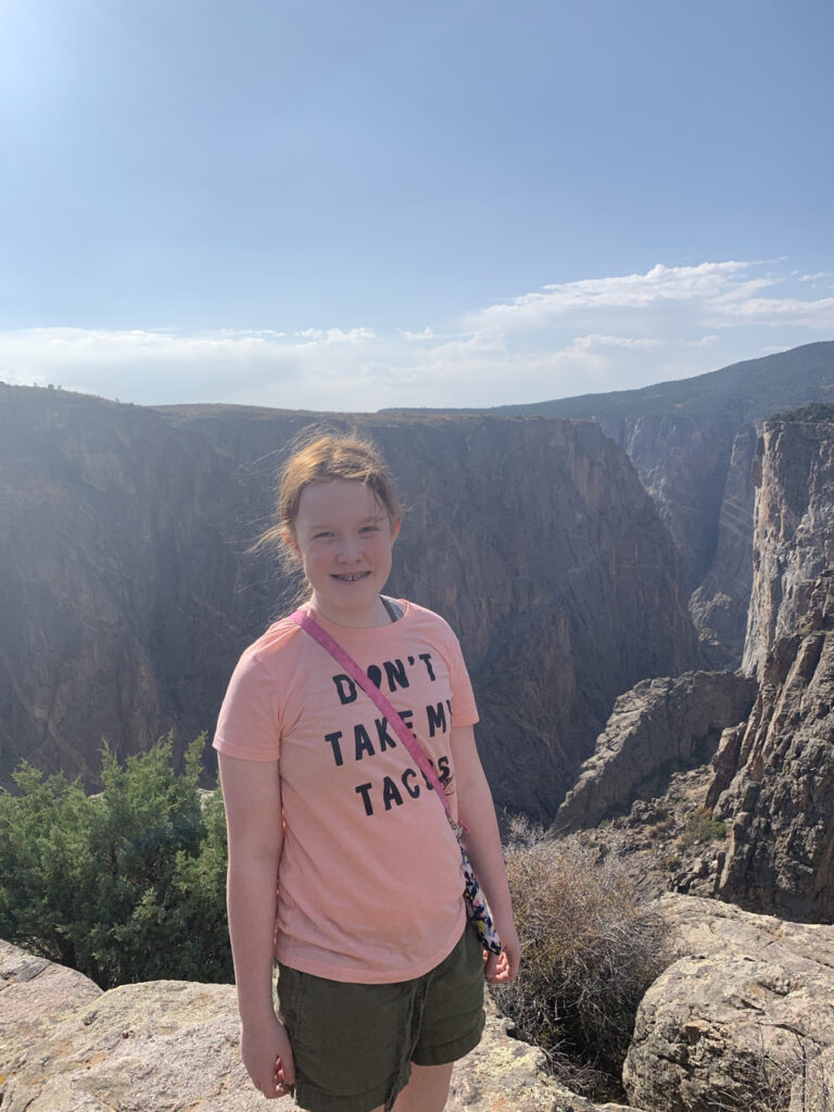 Cameron standing mid afternoon and smiling at the overlook at Narrow View in the Black Canyon of the Gunnison. 