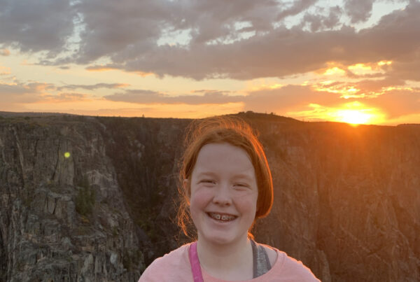 Cameron Standing up at sunset, with her red hair glowing for the last orange light of the day. Taken at the top of The Narrows Trails in Black Canyon of the Gunnison.