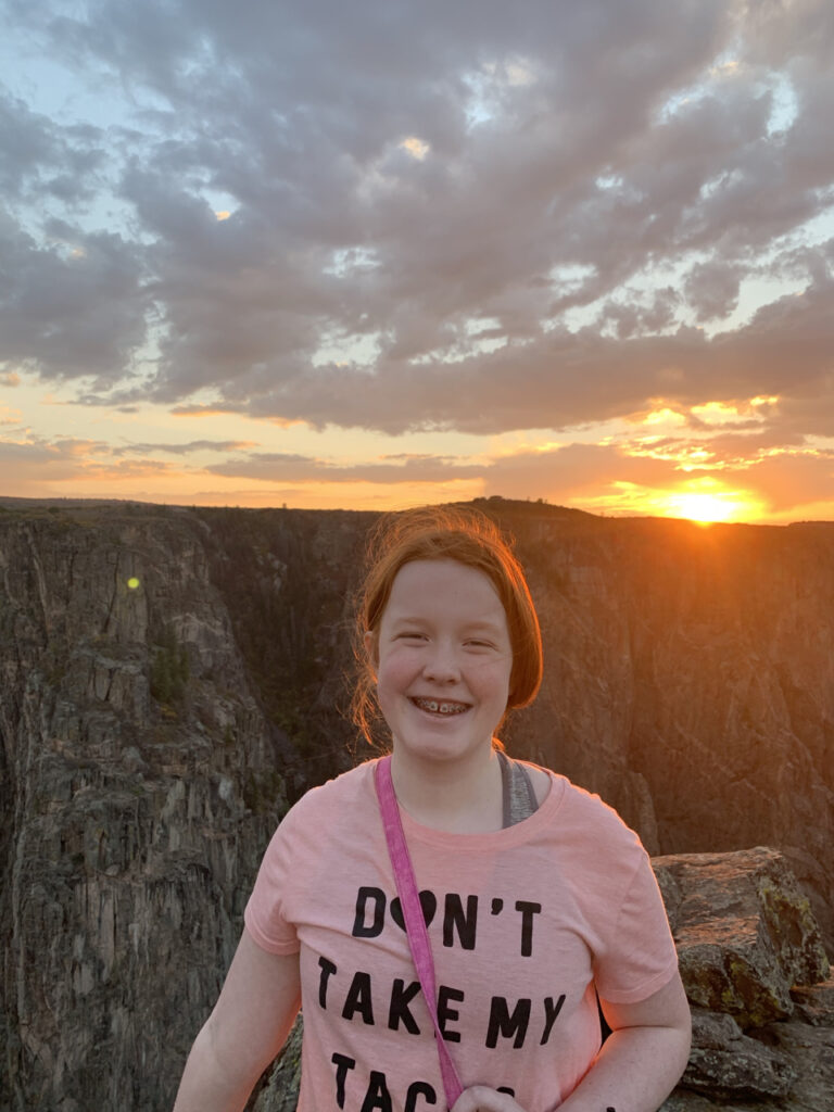 Cameron Standing up at sunset, with her red hair glowing for the last orange light of the day. Taken at the top of The Narrows Trails in Black Canyon of the Gunnison. 