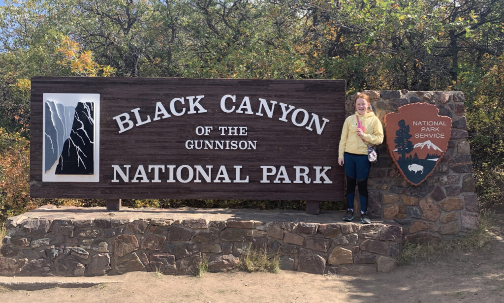 Cameron smiles while standing on the sign for the Black Canyon of the Gunnison National Park.