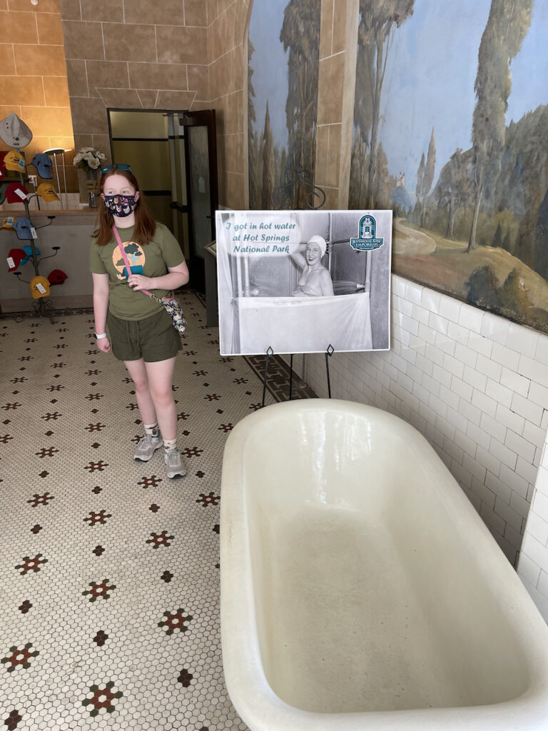 Cameron standing by a very old bathtub with very old tile woke on the ground. This is inside the visitors center to Hot Springs National Park. 