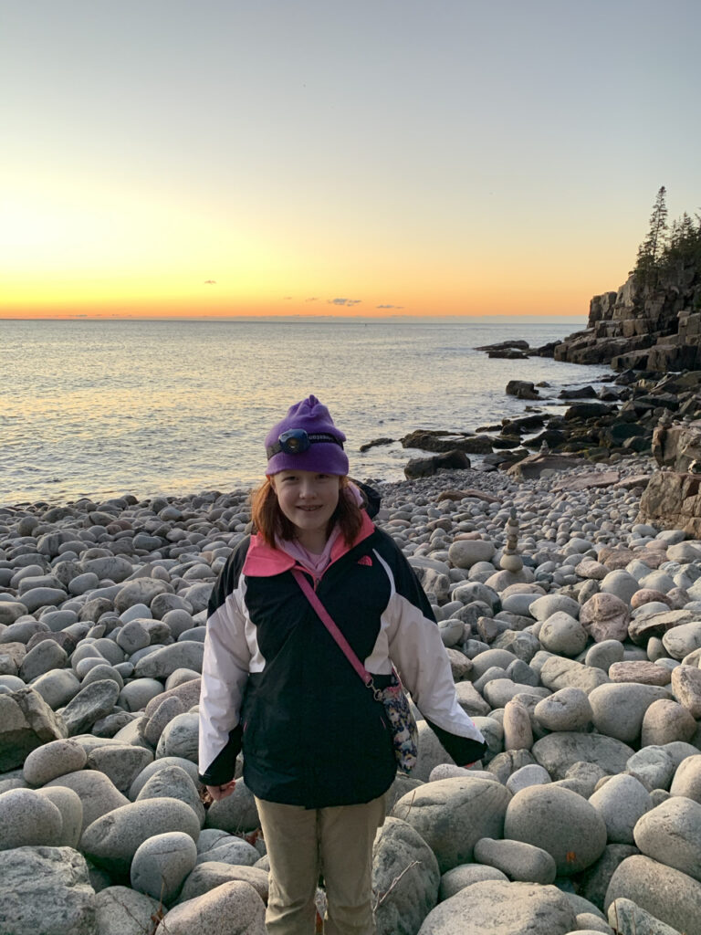 Cameron standing on Boulder Beach at sunrise in Acadia National Park.