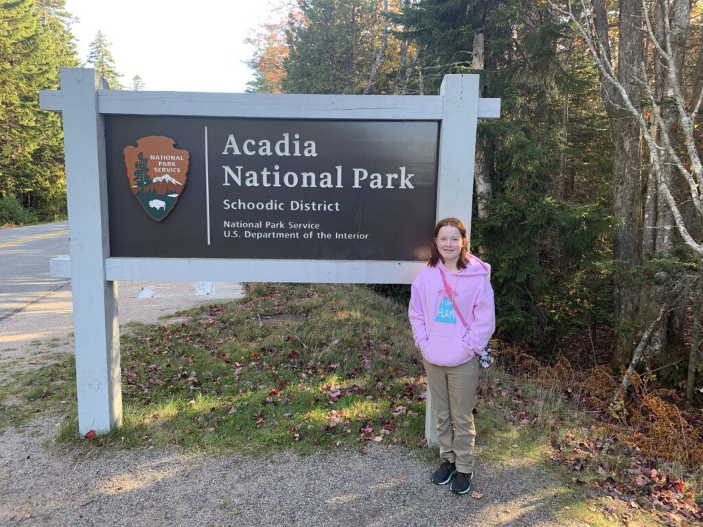 Cameron standing in front of the Acadia National Park sign in the Schoodic District of the park. Taken at the peak of fall color in Maine. 