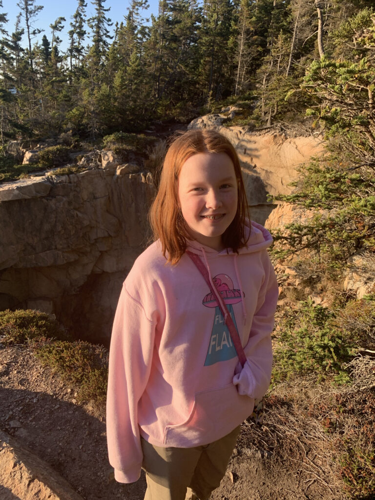 Cameron on the cliffs edge near the Ravens Nest in Acadia National Park. The warm sunset light is covering the entire scene. 