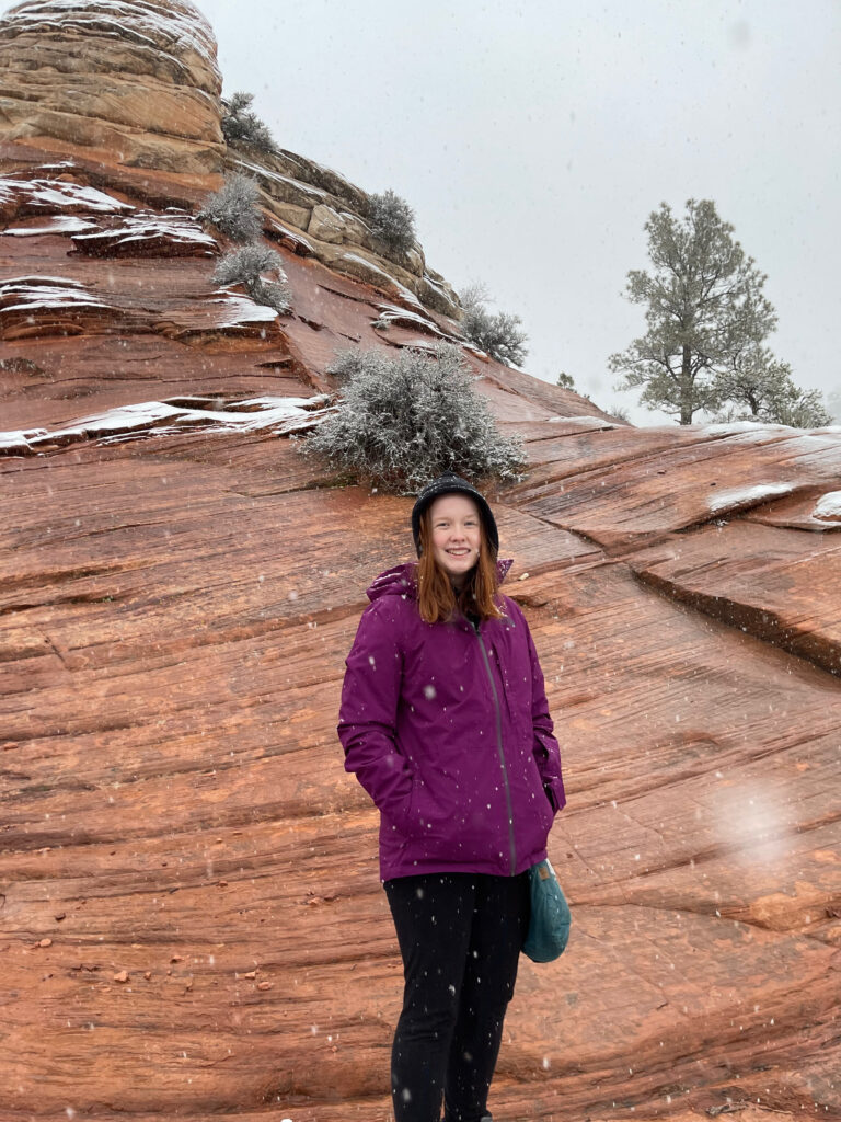 Cameron stopping on a hike up the steep and wet sandstone on the east side of Zion. Its snowing and the rock is both wet and covered in snow. 