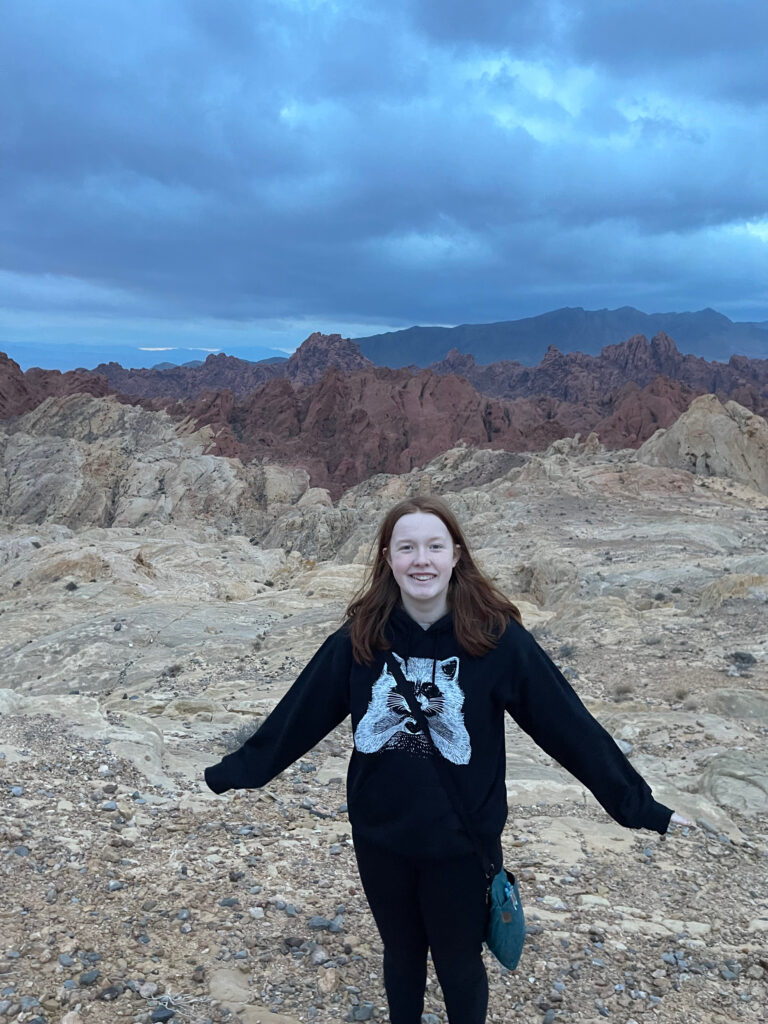 Cameron at dawn in the Valley of Fire state park. Standing in front of the main valley with a cloudy skies overhead. 