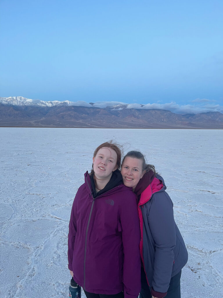 Cat and Cameron standing pre-dawn wearning jackets in the middle of the salt flats past badwater basin in Death valley National Park.