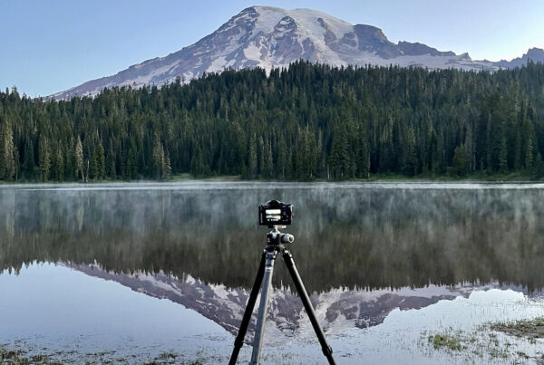 My camera on a tripod at Reflection Lake at Mount Rainier. The mountain is fully reflected int the water in front of me.