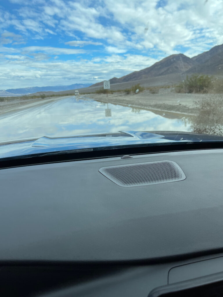 A view from inside my car, driving down the flooded road in Death Valley. The road is totally covered in water.