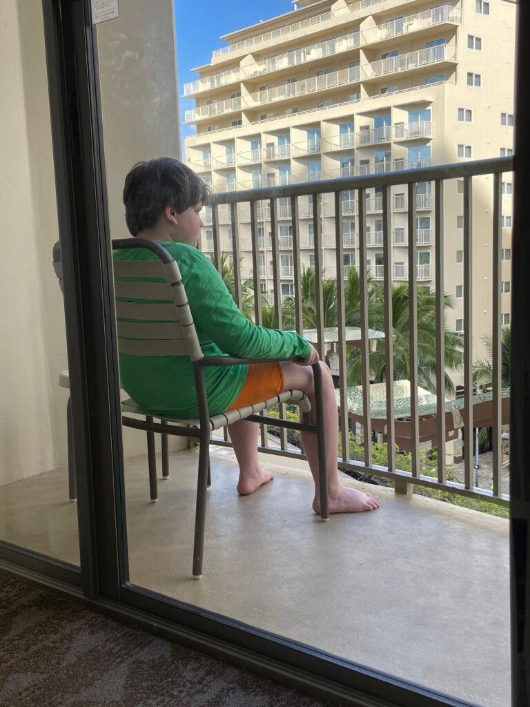 Collin sitting alone on the hair on the balcony of out hotel room in Waikiki.