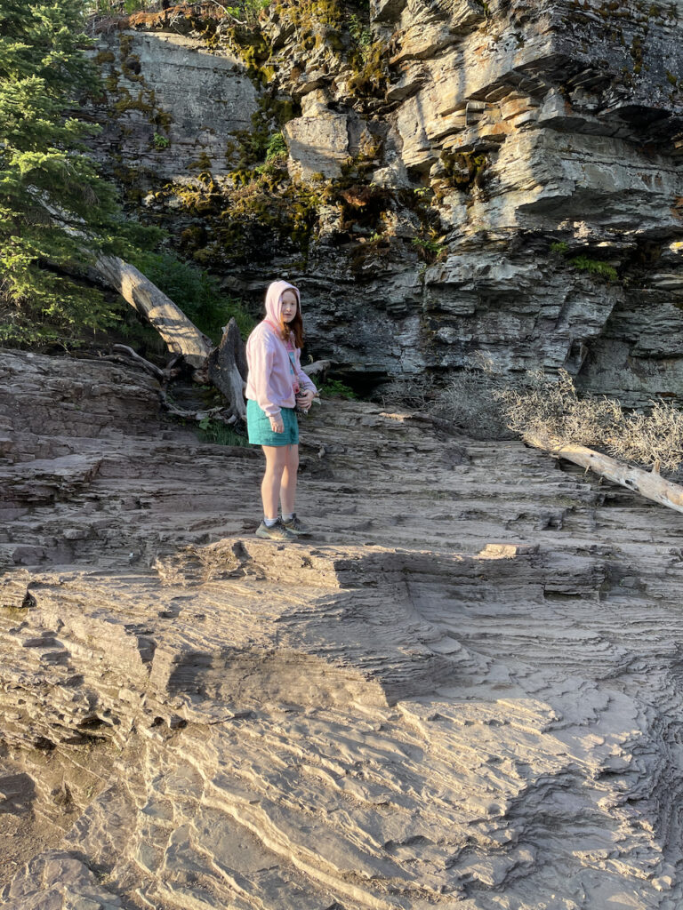 Cameron climbing up rocks in the first light of the morning looking back and all smiles in Glacier National Park.