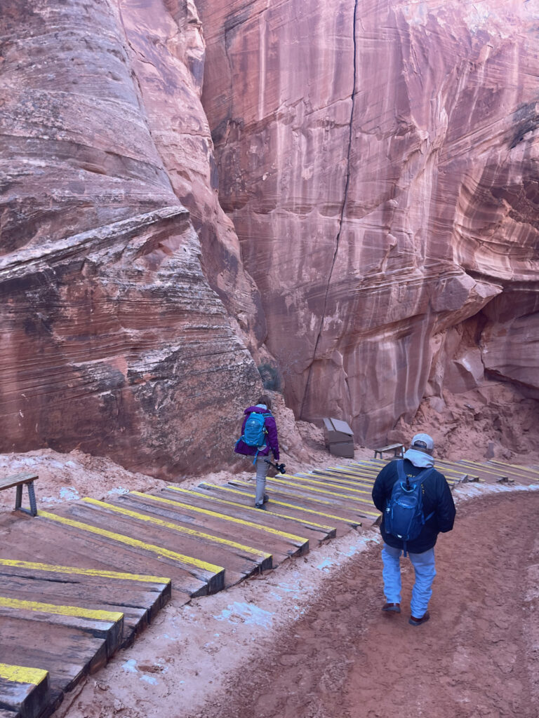 Cameron walking down the massive steps into the slots canyons in the winter, with snow and ice on the ground outside of Page Arizona. 