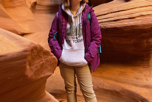 Cameron standing deep in Rattlesnake Canyon in Page AZ. The light is filtered down through the canyon as she looks up at the impressive sandstone.