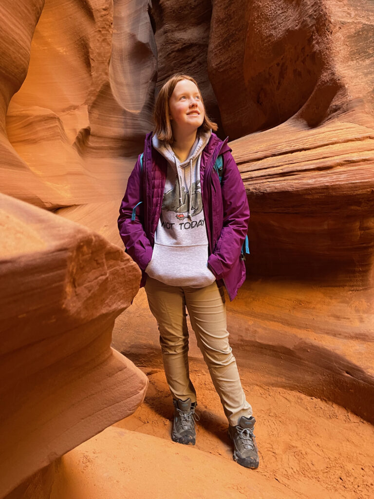 Cameron standing deep in Rattlesnake Canyon in Page AZ. The light is filtered down through the canyon as she looks up at the impressive sandstone.