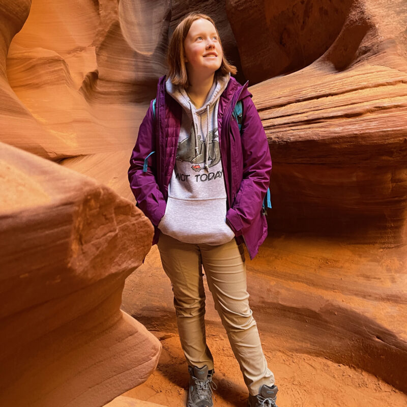 Cameron standing deep in Rattlesnake Canyon in Page AZ. The light is filtered down through the canyon as she looks up at the impressive sandstone.