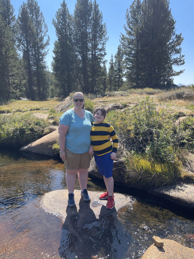 Cameron and Collin all similes as they stand on a rock at the edge of the Dans Fork river in the high country of Yosemite National Park.