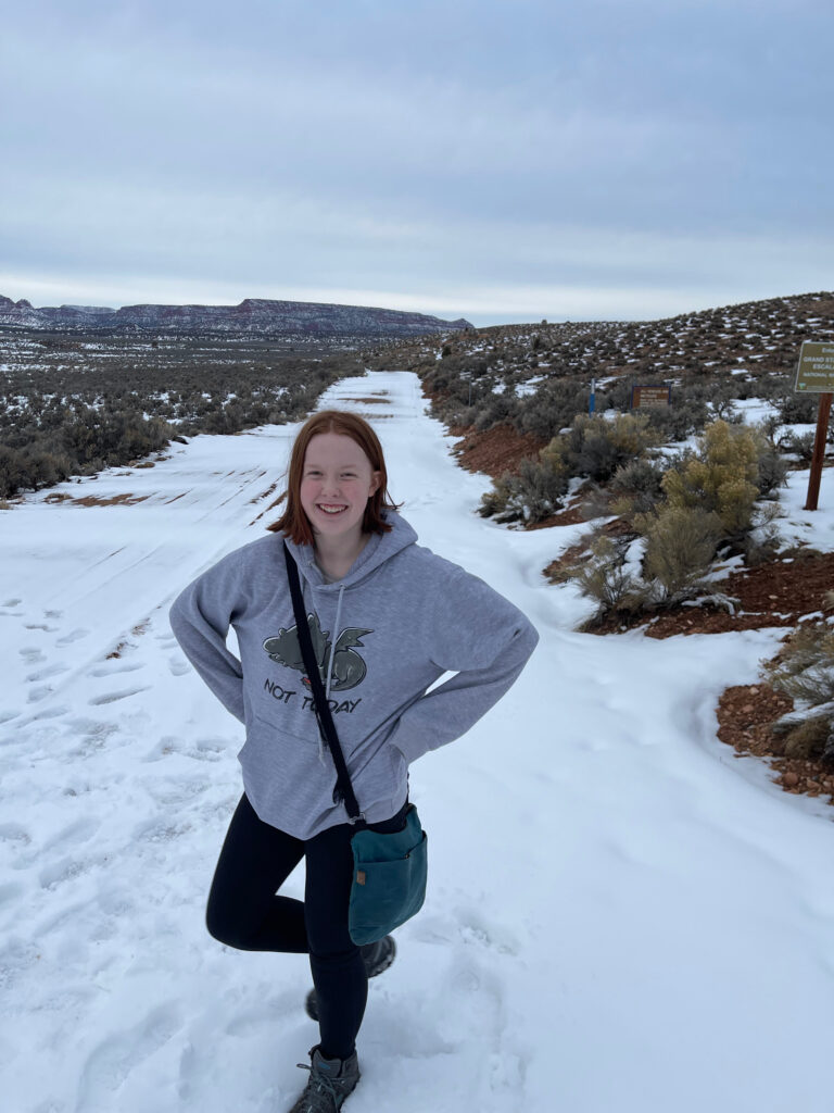 Cameron in a hoodie standing on one leg on a dirt trail that leads deep into the Grand Staircase National Monument. 