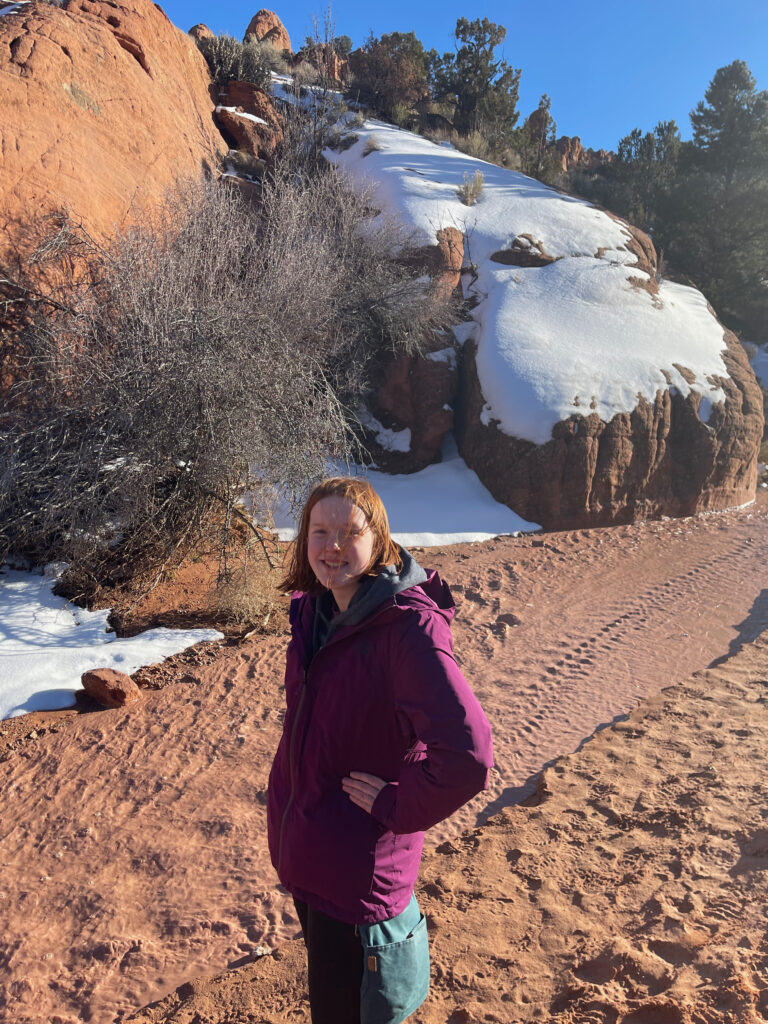 Cameron standing next to a tiny creek near Catstair Canyon in the Grand Staircase Escalante National Monument.  Snow is on the rock walls in thje background.