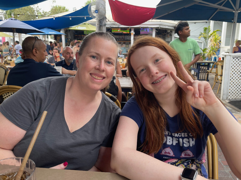 Cameron and Cat sitting at an outdoor dinning table in Key West. Both are smiling and Cami is making a peace sign. About to have dinner at Fogarty's.