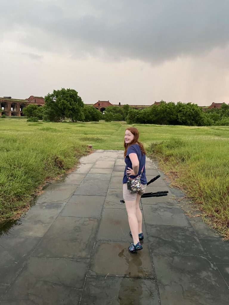 Cameron carrying my tripod and looking back at me while walking through the massive center courtyard of Fort Jefferson just as the rain had started. 