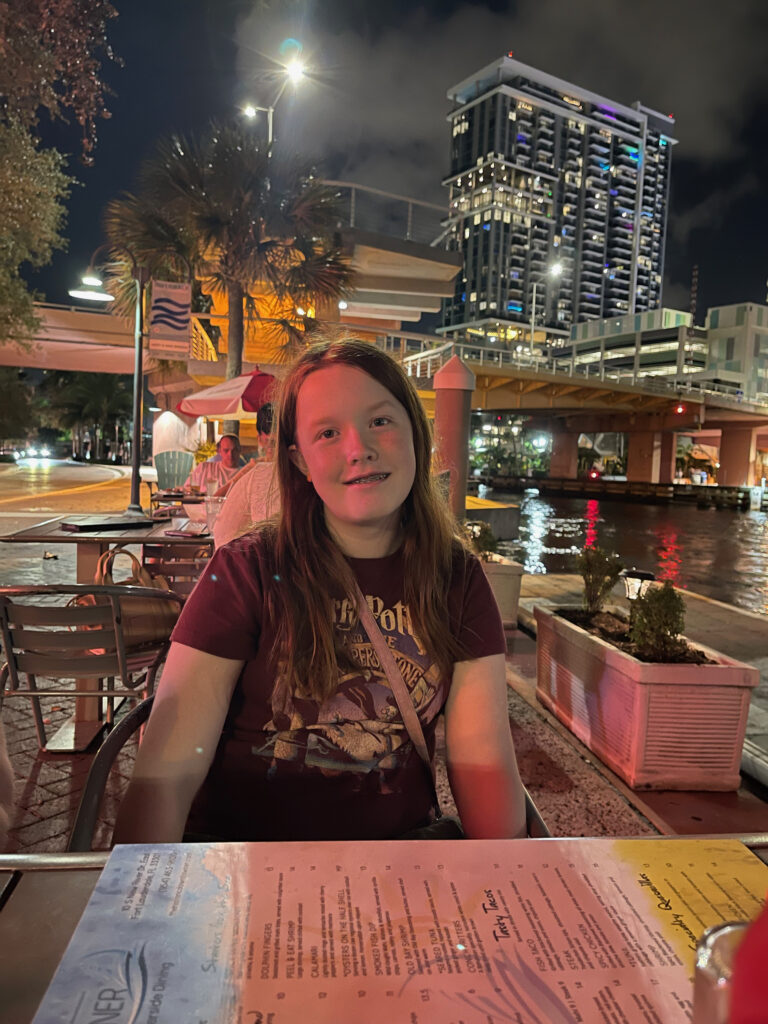 Cameron at at outdoor restaurant in Fort Lauderdale eating outside by the river at night with all the building behind us.