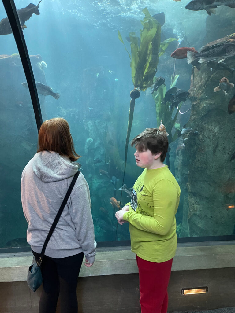 Cameron and Collin standing in the glass tunnel in the Oregon Coast Aquarium looking at all the sea life. 