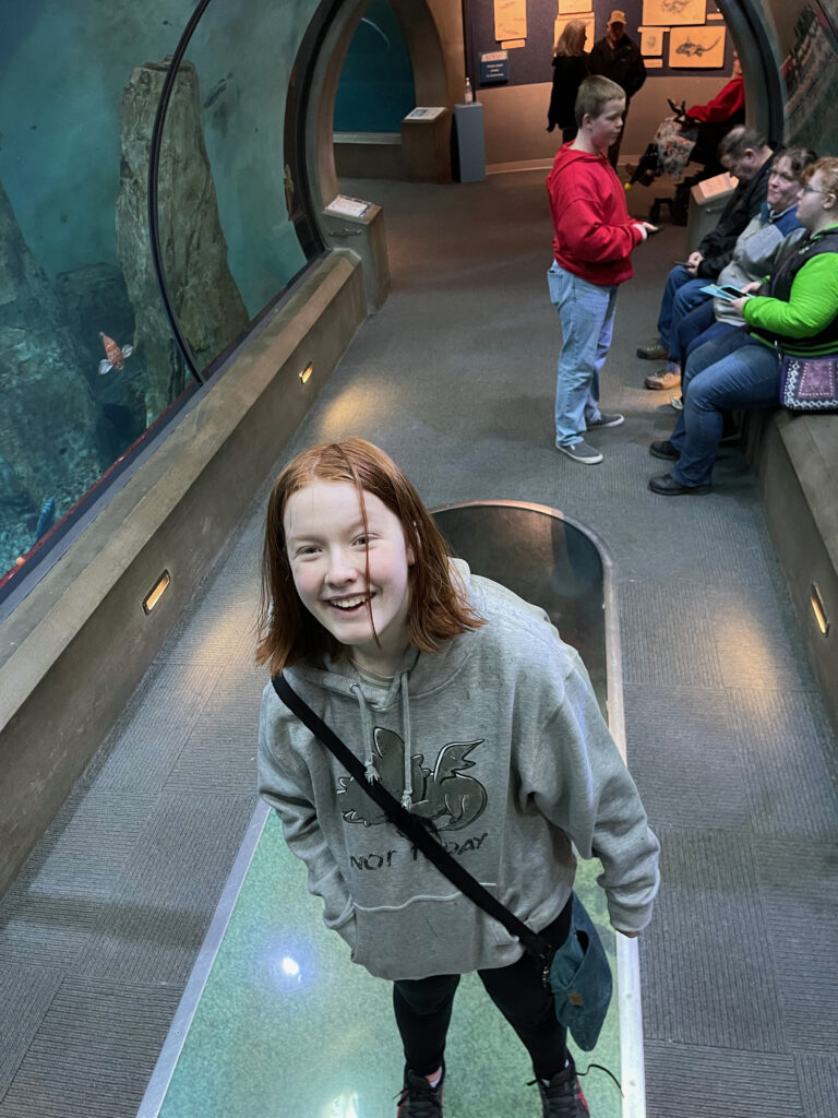 Cameron all smiles standing in the glass tube in the Oregon Coast Aquarium.