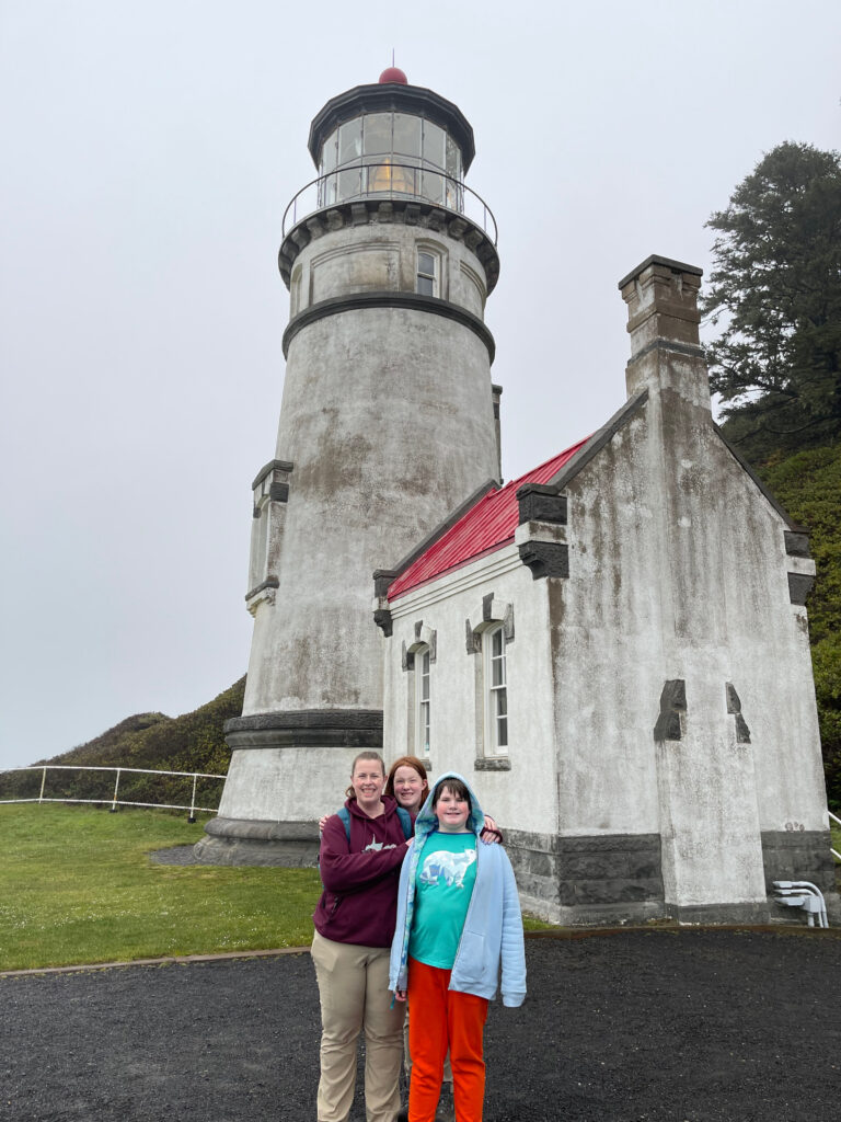 Cat, Cameron and Collin in front of the Heceta Lighthouse on a rainy day.