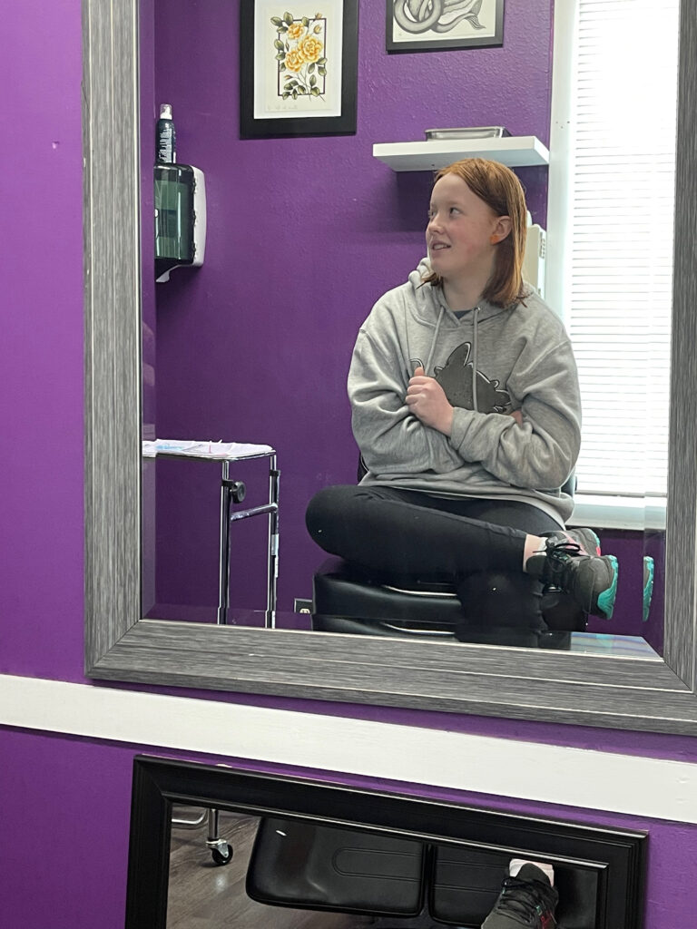 Cameron sitting on a chair and looking a bit worried as she is about to get her ears pierced at Ago Fine Jewelry and Piercing.