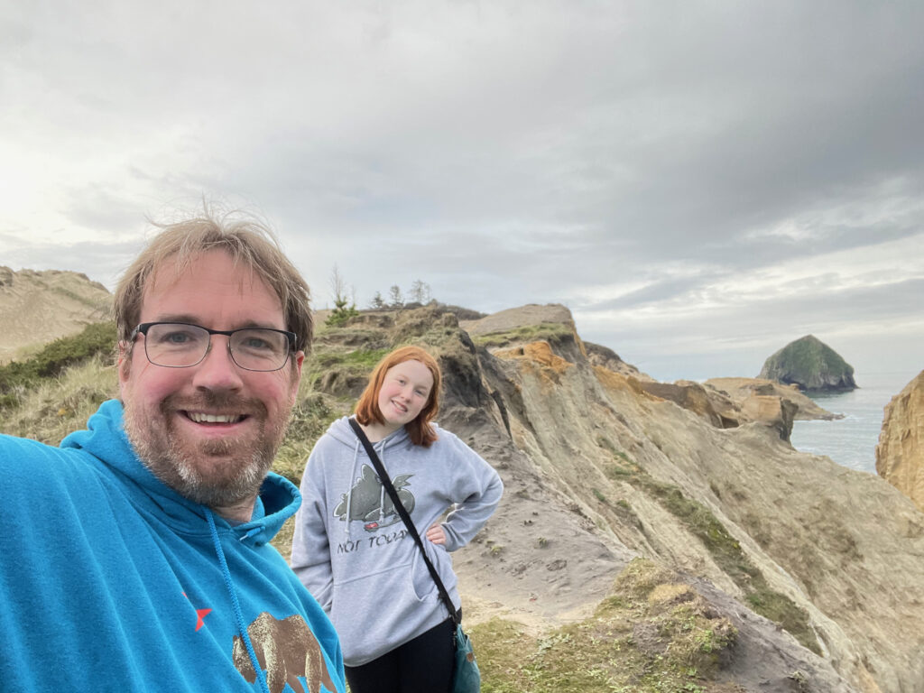 Cameron and myself both wearing hoodies and smiling on top of the dunes at Cape Kiwanda State Park.