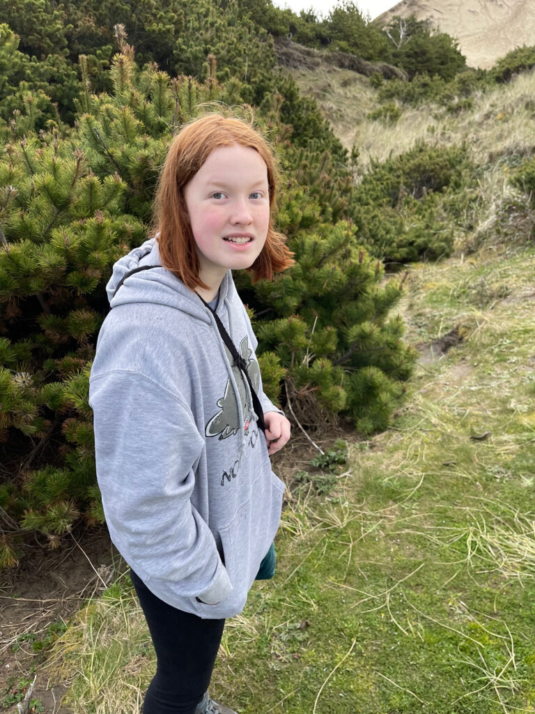 Cameron wearing a hoodie on top of a dunes at Cape Kiwanda State Natrual Area.