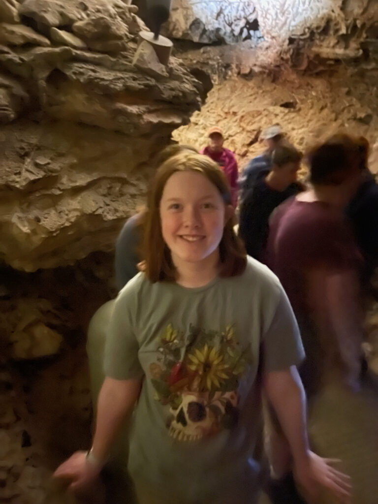 Cameron in a narrow passageway deep inside Wind Cave on a tour with many people in the background.